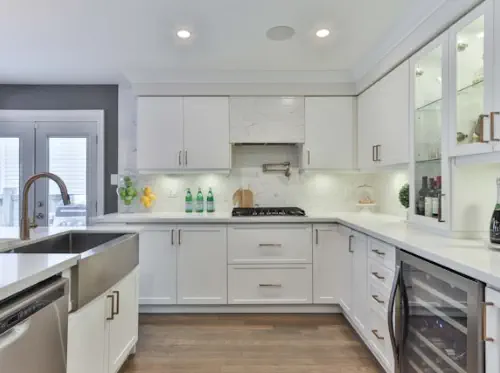 Two cars have been in a fender-bender. A woman stands, talking into a cell phone. A man sits on the ground looking at his cell phone.