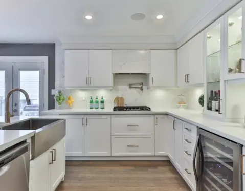 Two cars have been in a fender-bender. A woman stands, talking into a cell phone. A man sits on the ground looking at his cell phone.